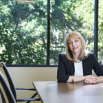 Andrea Auerback sitting at a desk, trees in background