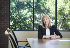 Andrea Auerback sitting at a desk, trees in background