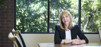 Andrea Auerback sitting at a desk, trees in background