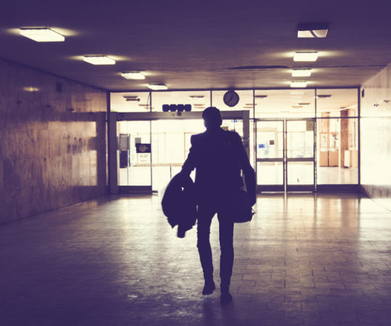 Silhouette of man walking through an empty hallway.